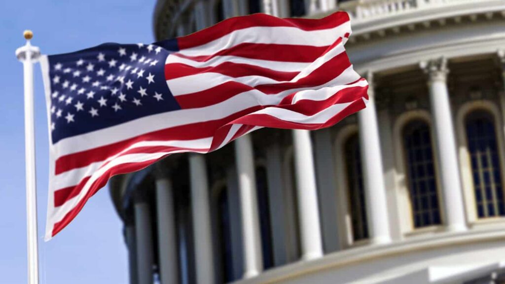 The flag of the United States of America flying in front of the Capitol building